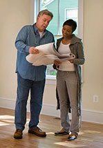 A man and woman looking at plans in a room.