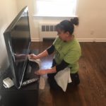 A woman is cleaning the tv on the floor