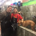 A man and his dog in the shower with their owner.